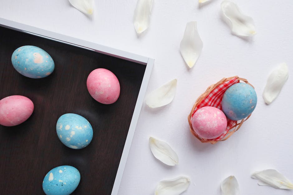 Top view of pastel blue and pink Easter eggs with white petals on a tray and basket.