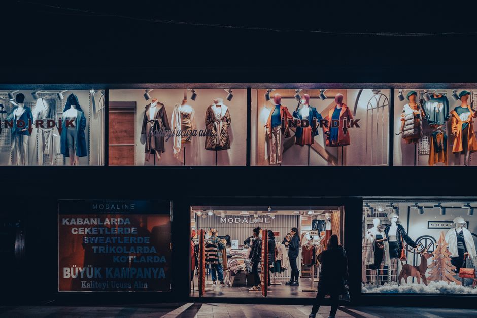 Illuminated fashion store window with mannequins and dramatic lighting at night.